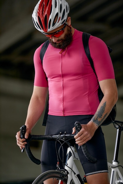 Foto retrato de um ciclista em pé debaixo de uma ponte com uma bicicleta na mão posando para a câmera contra um fundo de arquitetura estilo de vida ativo andar de bicicleta é um hobby