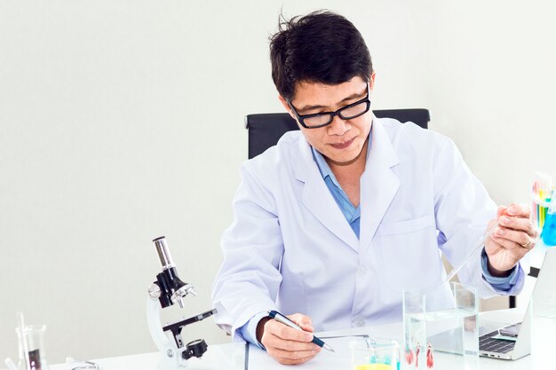 Foto retrato de um cientista maduro sorridente em um jaleco branco com lupa.