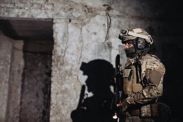 Retrato de um defensor ucraniano no banco Um soldado com uma arma nas mãos lança uma sombra na parede