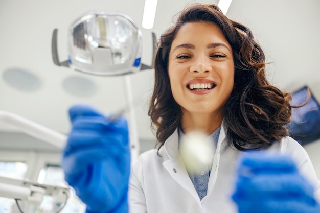 Foto retrato de um dentista feliz inclinado e fazendo um exame no consultório do dentista