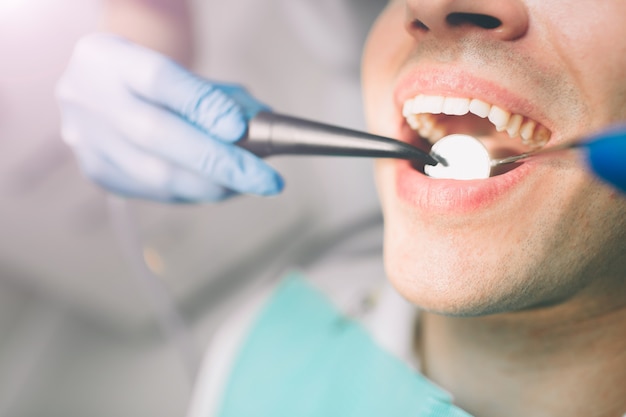 Retrato de um dentista que trata os dentes do paciente jovem.