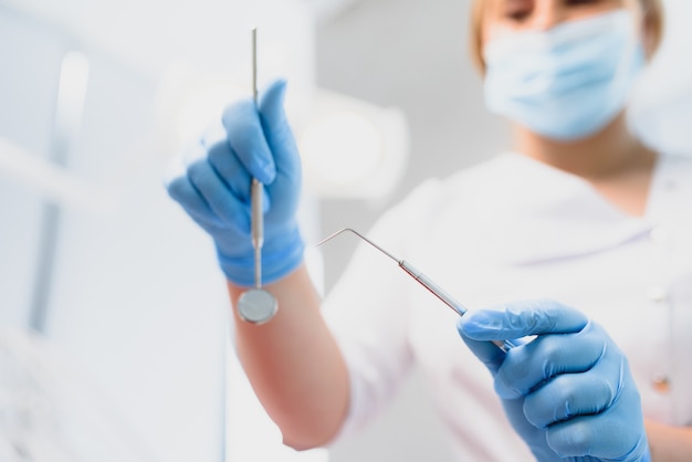 Retrato de um dentista segurando instrumentos odontológicos nas mãos em close-up da clínica