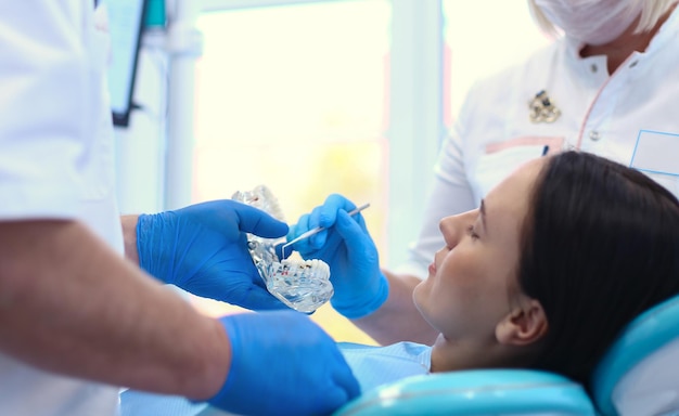 Retrato de um dentista sorridente em pé na clínica odontológica