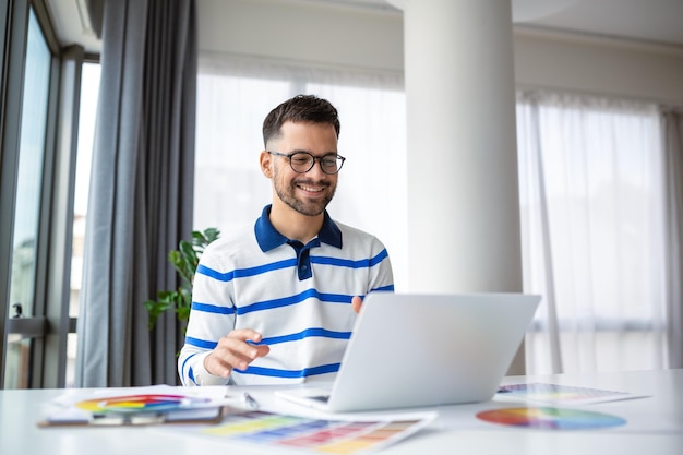 Retrato de um designer de interiores masculino trabalhando no escritório com amostras de cores homem no local de trabalho escolhendo amostras coloridas close-up conceito de pessoas criativas