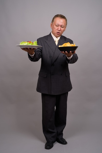 Retrato de um empresário asiático maduro contra uma parede cinza