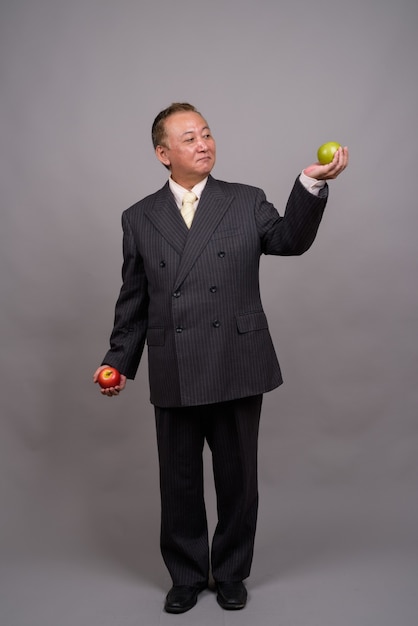 Retrato de um empresário asiático maduro contra uma parede cinza