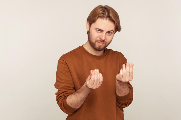 Foto retrato de um empresário barbudo bonito e inteligente em moletom estiloso mostrando gesto de dinheiro planejando grande renda