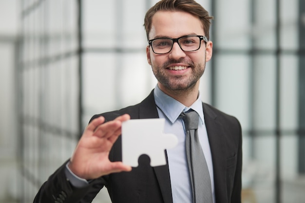 Foto retrato de um empresário barbudo otimista segurando peças de quebra-cabeça resolvendo tarefas olhando para a câmera