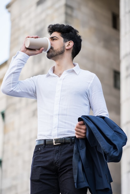 Retrato de um empresário bebendo uma xícara de café a caminho de trabalhar ao ar livre. conceito de negócios.