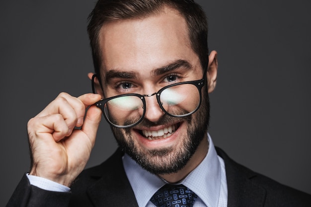Retrato de um empresário bonito e confiante vestindo um terno de pé isolado, posando com óculos