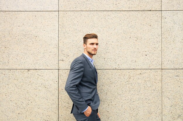 Retrato de um empresário bonito em um terno do lado de fora de um prédio da cidade.