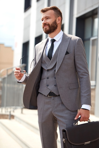 Retrato de um empresário caucasiano bonito com uma mala indo para uma reunião de negócios