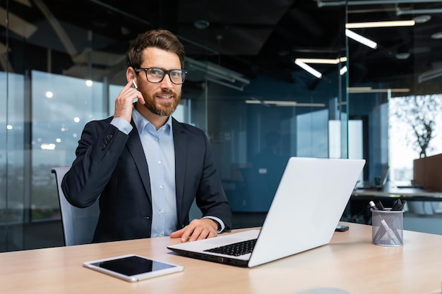 Retrato de um empresário de sucesso dentro de um escritório moderno, um homem de terno usa fones de ouvido