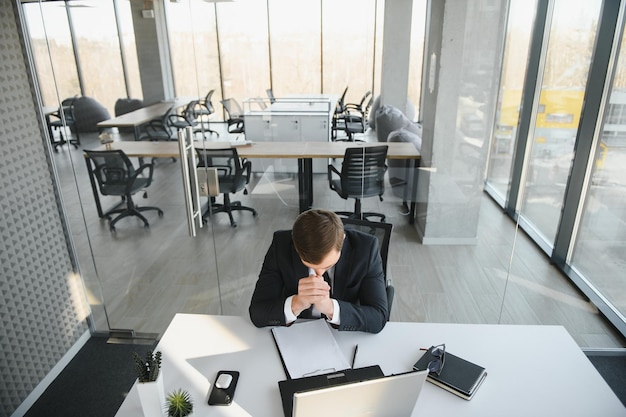 Retrato de um empresário estressado e preocupado, sobrecarregado de trabalho, procurando relatórios de documentos em um escritório moderno e brilhante, trabalhando sob pressão e prazo apertado