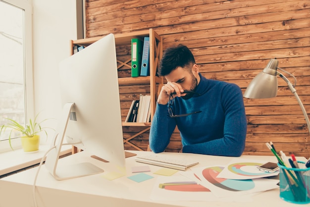 Retrato de um empresário exausto de óculos e tentando se concentrar