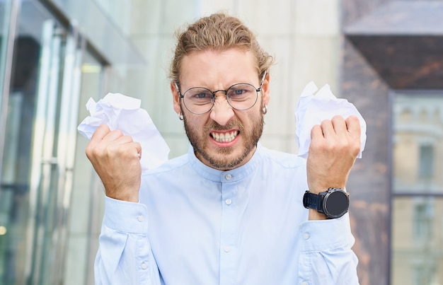 Retrato de um empresário furioso gritando e jogando papéis de negócios