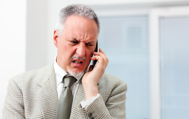 Retrato de um empresário irritado, gritando no telefone