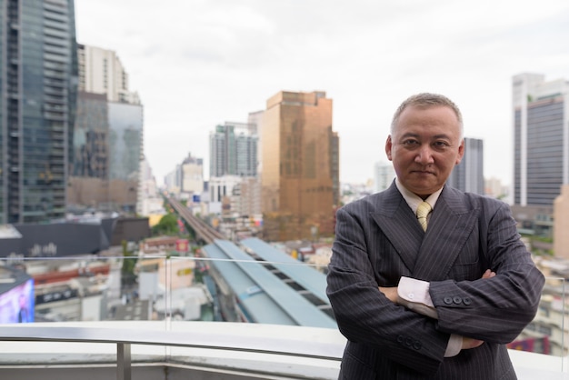 Retrato de um empresário japonês maduro em um terno contra a vista da cidade