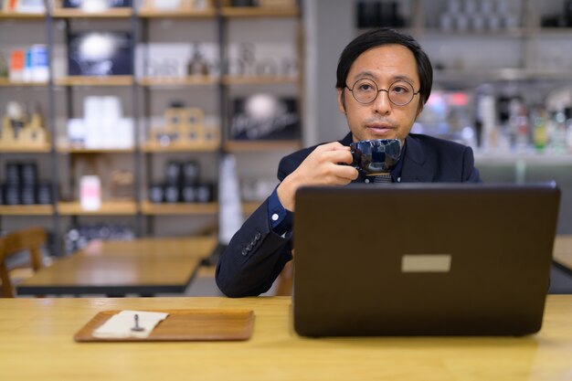 Retrato de um empresário japonês sentado dentro de uma cafeteria