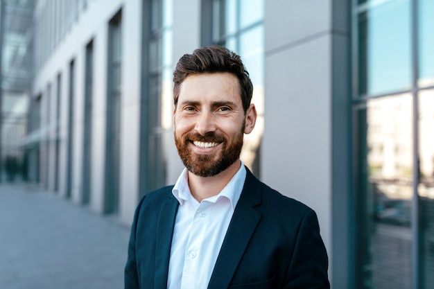 Retrato de um empresário milenar atraente e confiante sorridente com barba de terno olhando para a câmera