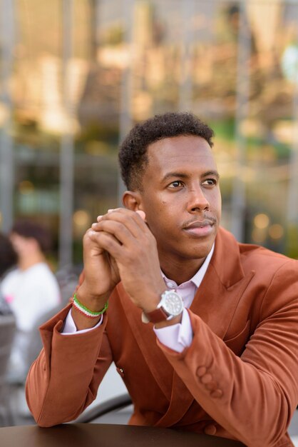 Retrato de um empresário negro africano bonito ao ar livre em um café pensando