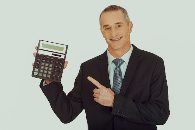 Foto retrato de um empresário sorridente apontando para uma calculadora contra um fundo branco