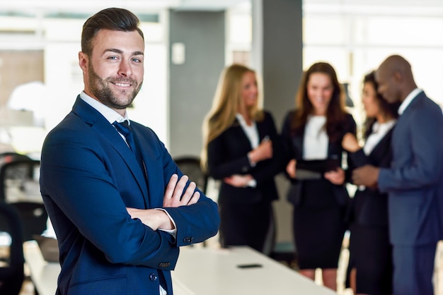 Retrato de um empresário sorridente e confiante ao lado de colegas no escritório