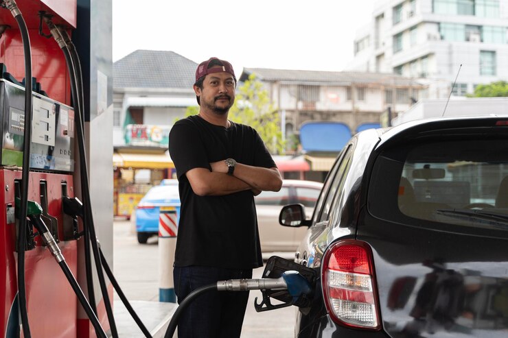 Retrato de um empresário sorridente reabastecendo seu carro de luxo no posto de gasolina Homem motorista reabastecendo e bombeando óleo de gasolina o carro com combustível no posto de combustível