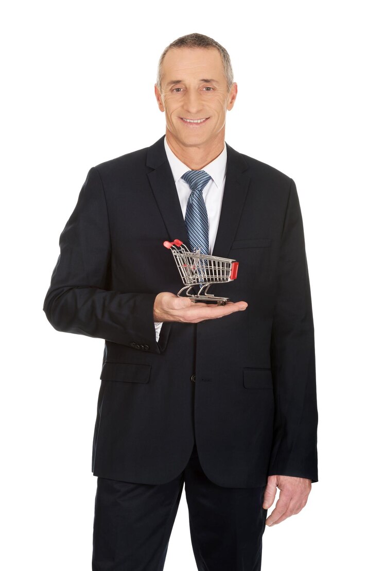 Foto retrato de um empresário sorridente segurando um carrinho de compras em miniatura enquanto está de pé contra um fundo branco
