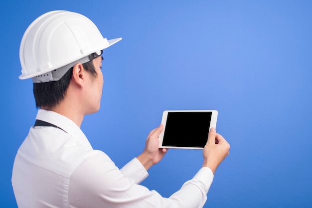 Retrato de um engenheiro confiante vestindo branco e usando tablet sobre azul