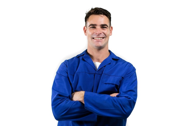 Retrato de um engenheiro masculino caucasiano feliz, com cabelo curto e escuro, em pé com os braços cruzados, vestindo roupas de trabalho, olhando para a câmera sorrindo sobre fundo branco