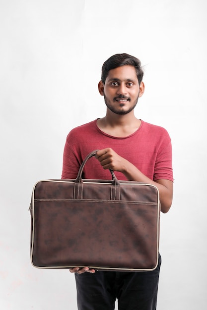 Retrato de um entregador de jovem feliz animado no boné de pé sobre um fundo branco e segurando o saco na mão.