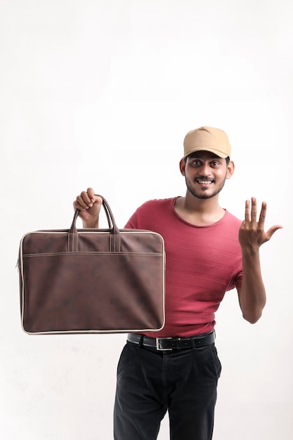 Foto retrato de um entregador de jovem feliz animado no boné de pé sobre um fundo branco e segurando o saco na mão.