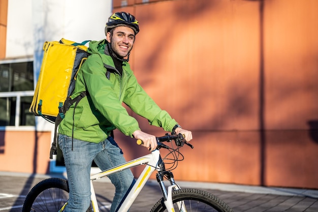Retrato de um entregador rápido sorridente no serviço de entrega expressa de comida e bebida de bicicleta no meio de transporte de sustentabilidade da cidade questão ambiental