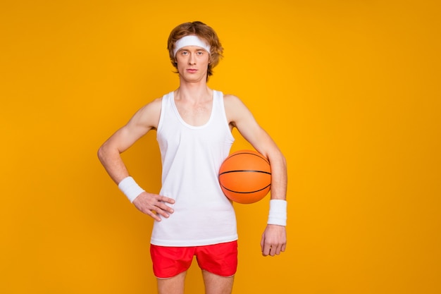 Retrato de um esportista sério segurando uma bola laranja