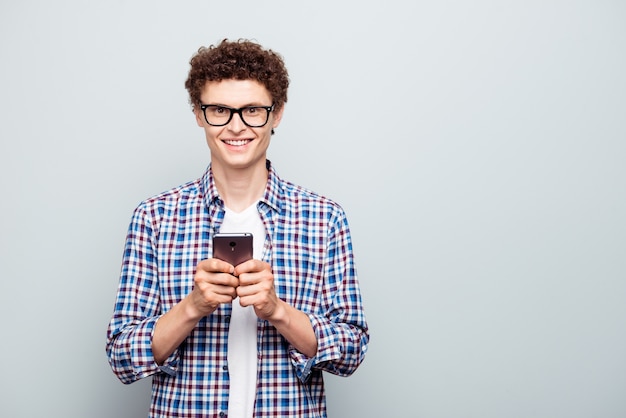 Retrato de um estudante feliz e inteligente segurando o smartphone nas mãos