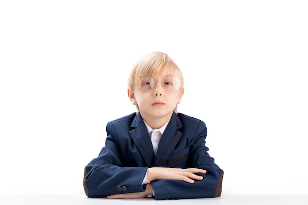 Retrato de um estudante loiro em fundo branco Estudante do ensino fundamental usa óculos sentado à toa na mesa Fidget boy