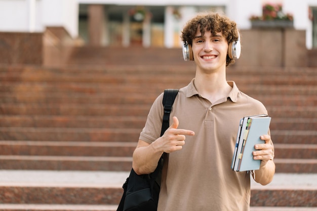 Retrato de um estudante masculino feliz e atraente segurando livros e passou em excelentes exames na universidade