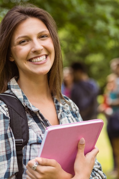 Retrato de um estudante sorridente com bolsa de ombro e livro de espera