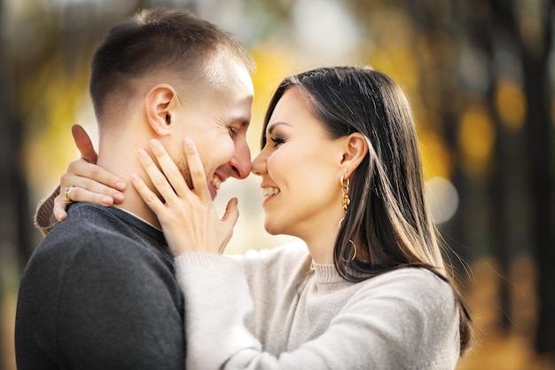 Retrato de um feliz casal de amantes de raça mista em um encontro rindo e se abraçando no parque de outono