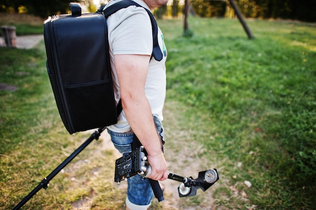 Retrato de um fotógrafo com tripé de mochila e outros equipamentos