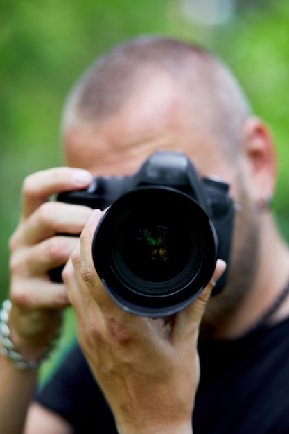 Retrato de um fotógrafo do sexo masculino cobrindo o rosto com a câmera