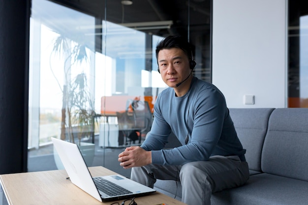 Retrato de um funcionário de call center asiático trabalhando com fone de ouvido e computador remoto ajuda on-line de videochamada