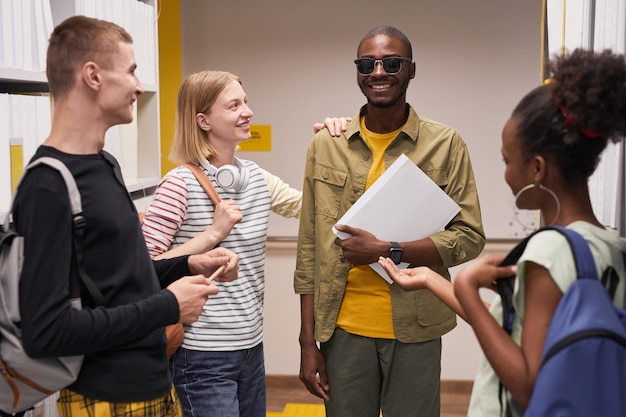 Foto retrato de um grupo diverso de alunos conversando com um cego sorridente