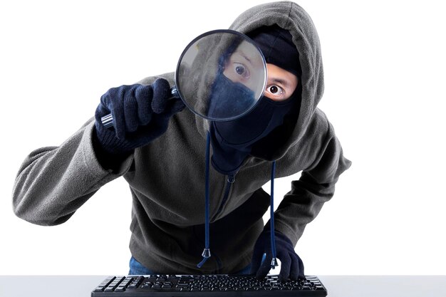 Foto retrato de um hacker olhando através de uma lupa contra um fundo branco
