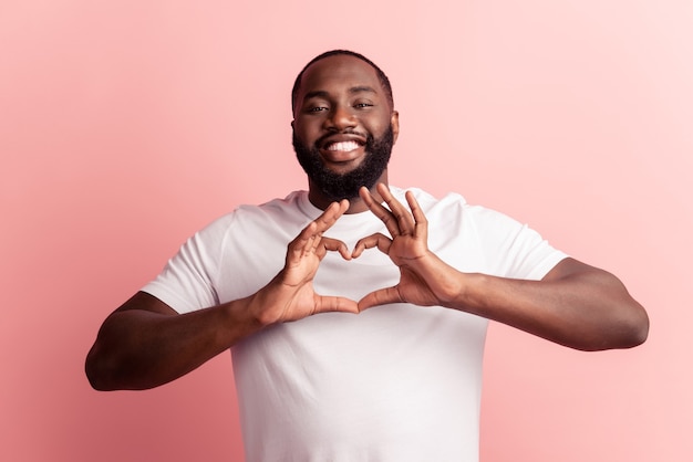 Retrato de um homem adorável feliz mostrando os dedos como um gesto de coração