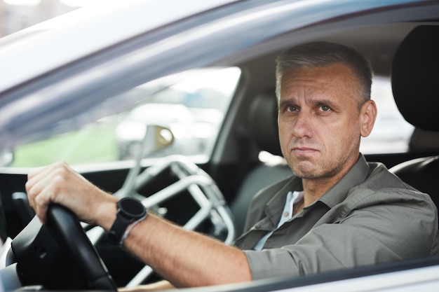 Retrato de um homem adulto com deficiência, dirigindo uma cadeira de rodas de carro em um espaço de cópia ao fundo