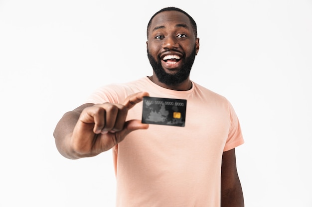 Retrato de um homem africano confiante e feliz, vestindo uma camisa em pé, isolado, mostrando o cartão de crédito