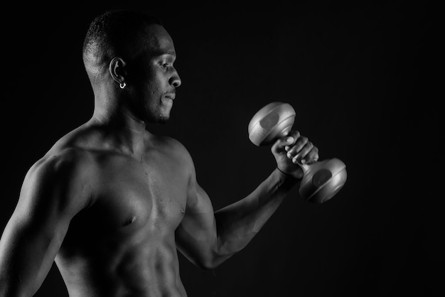 Retrato de um homem africano feliz com halteres sobre fundo vermelho