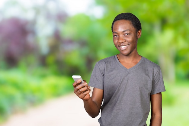 Retrato de um homem Africano sorridente usando smartphone sobre fundo branco